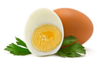 one egg and half a boiled egg with parsley leaves on a white background